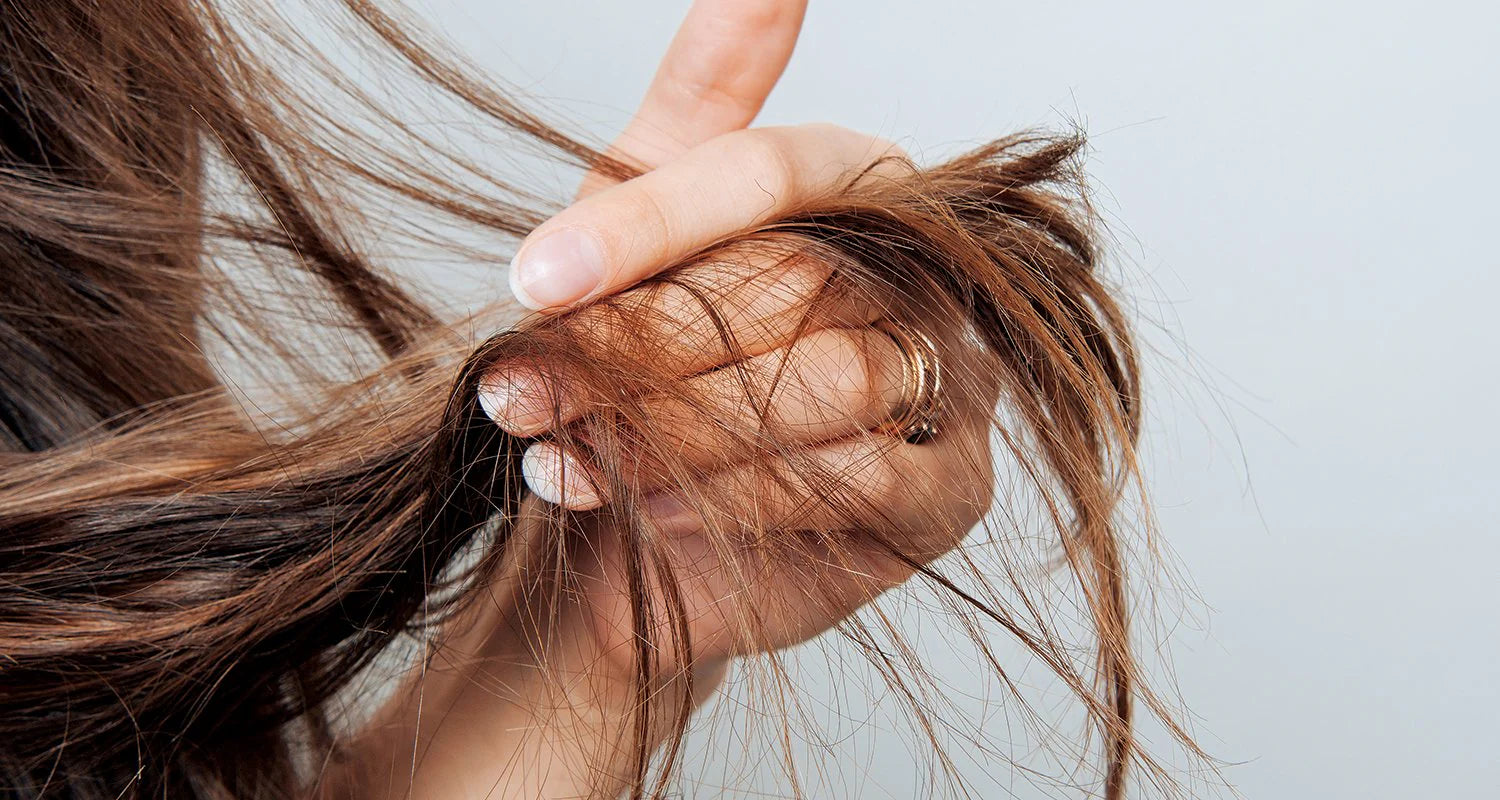 A woman inspecting her brittle and dry hair