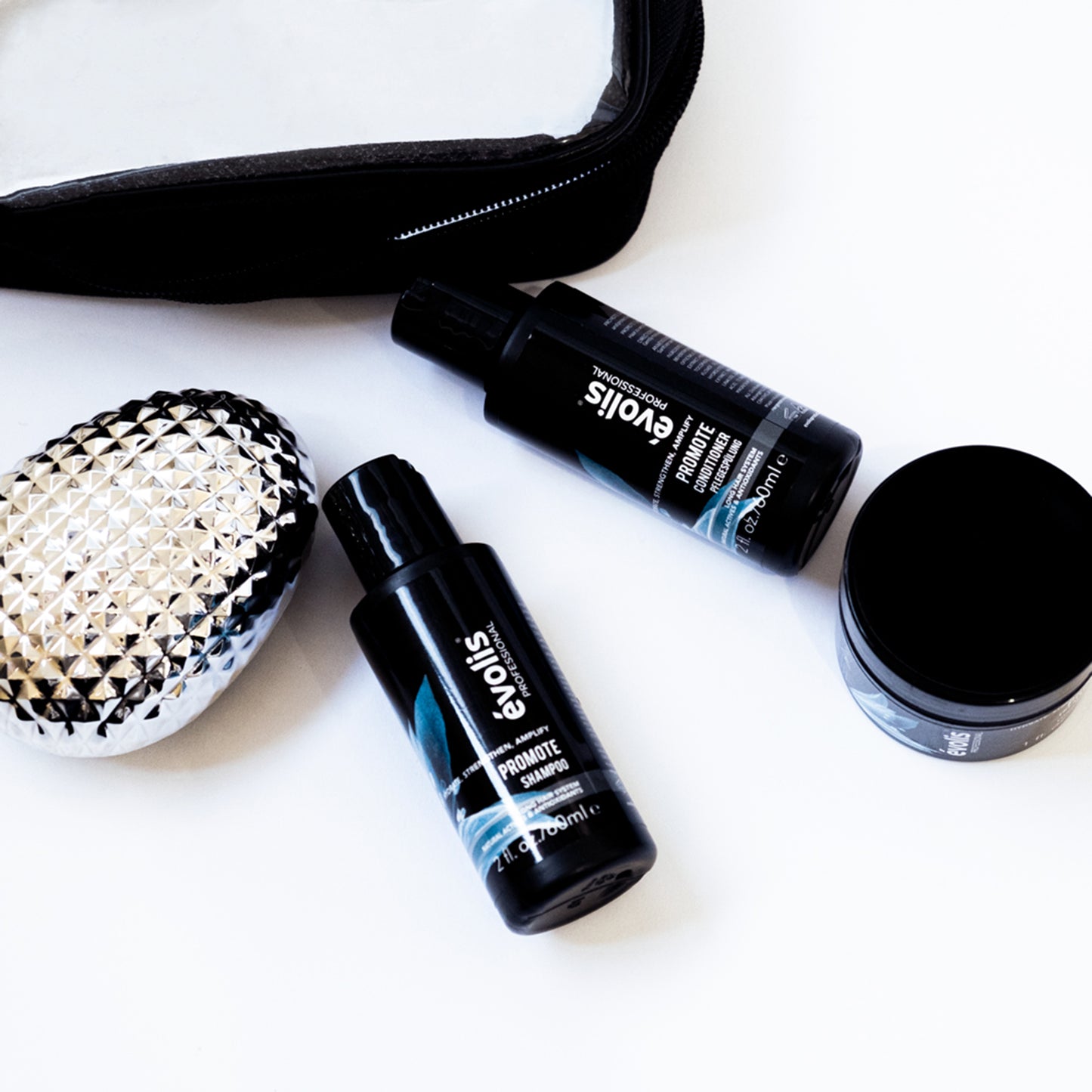 A stylized photo of the Evolis Promote products in travel size (shampoo, conditioner, & mask)