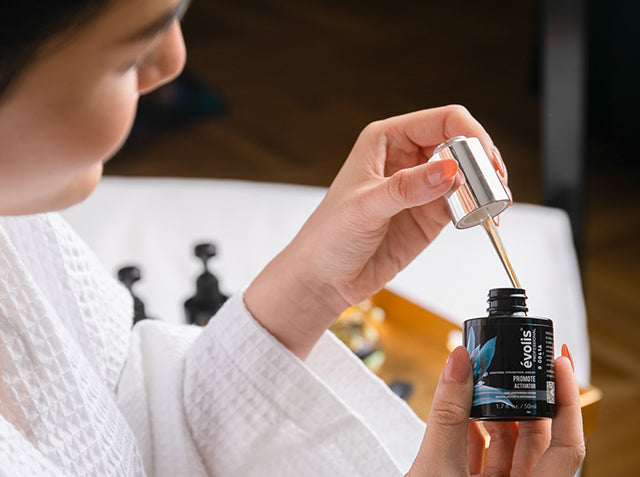 Woman opening the Evolis Promote Activator bottle with dropper
