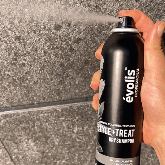 A woman spraying the Evolis Style + Treat dry shampoo