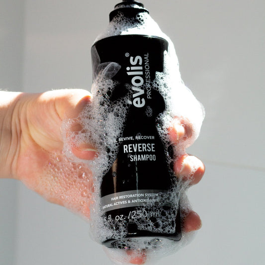 Man holding the Evolis Reverse Shampoo bottle in the shower