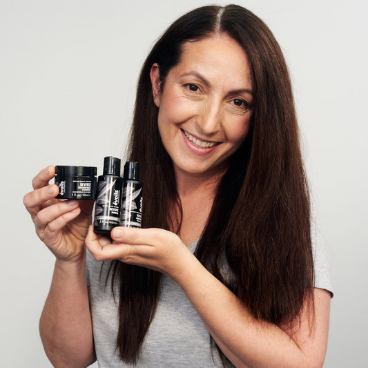 A woman holding the Evolis Reverse Products in Travel Size (Shampoo, Conditioner, & Treatment Mask)